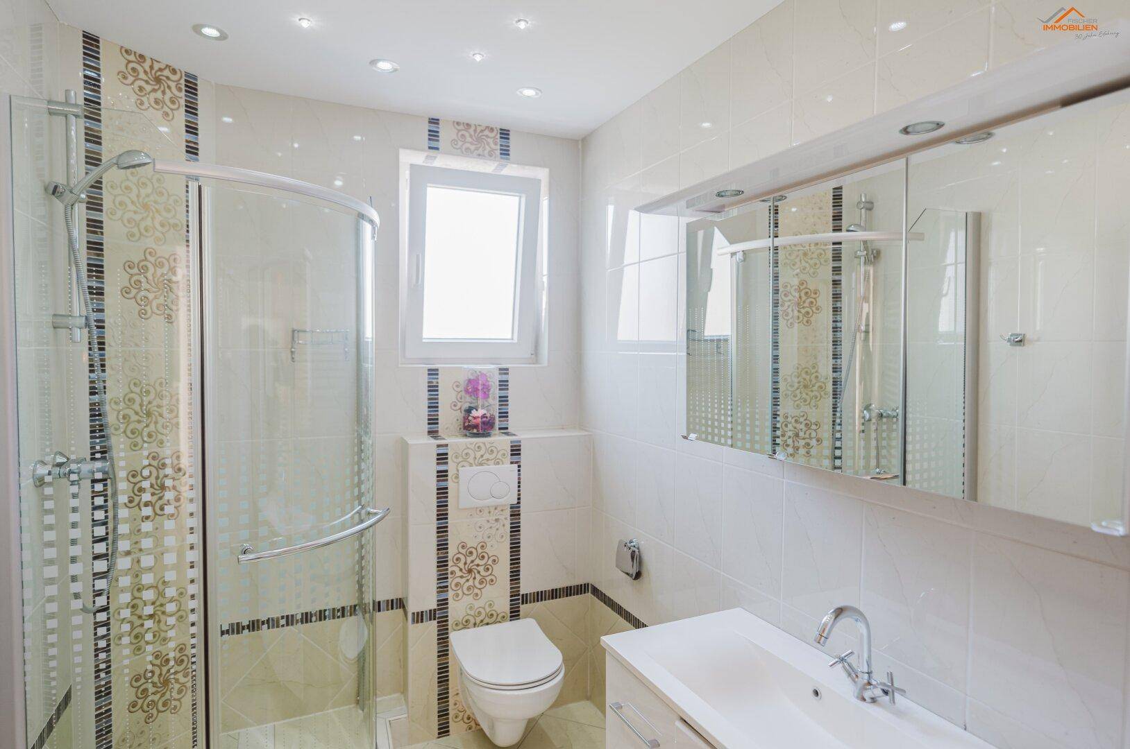 Modernes Badezimmer mit Duschkabine, Wand-WC und eleganten Fliesen in Beige- und Brauntönen.
