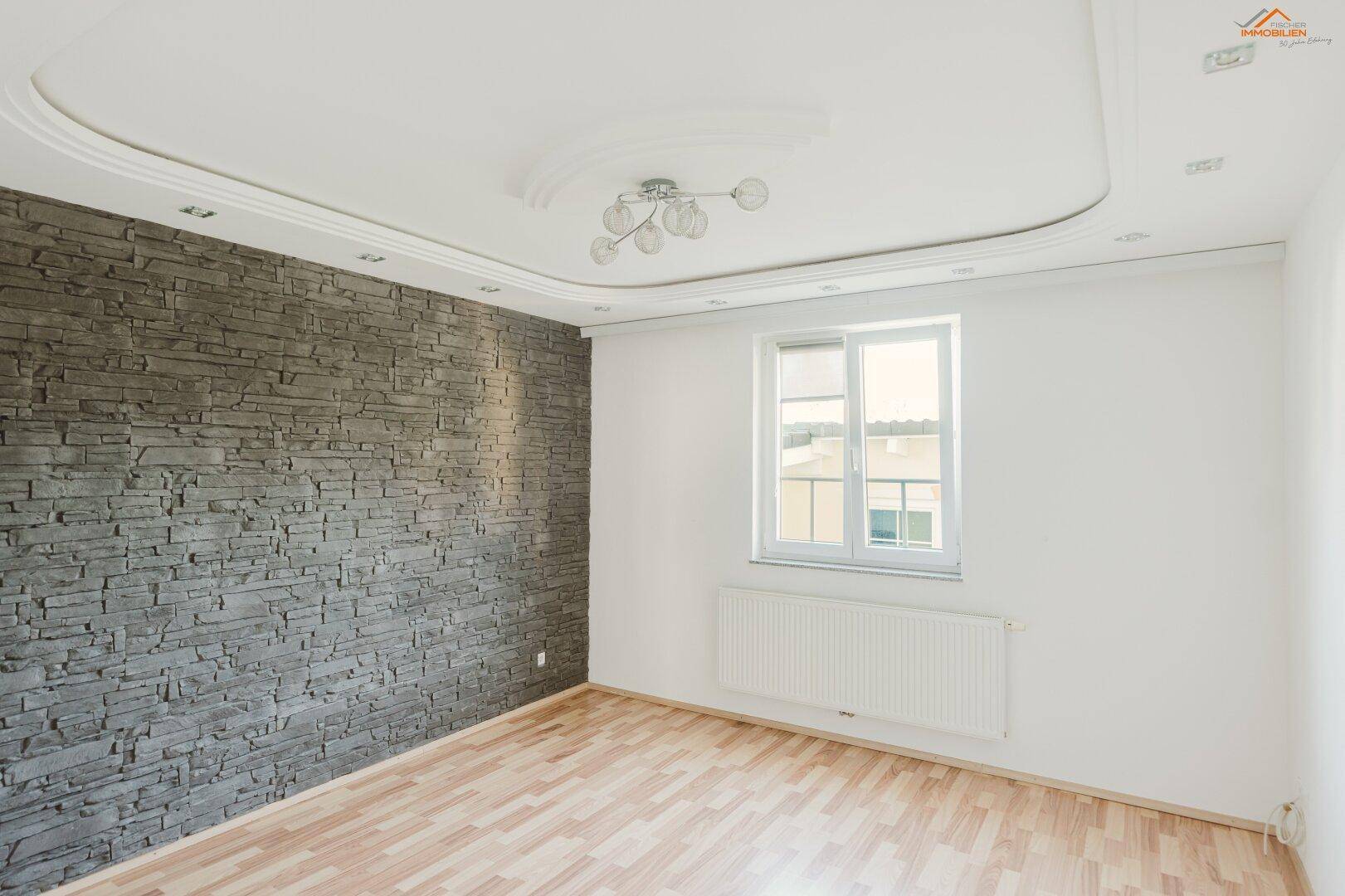 Helles Schlafzimmer mit Holzboden, dekorativer Steinwand und indirekter Deckenbeleuchtung.