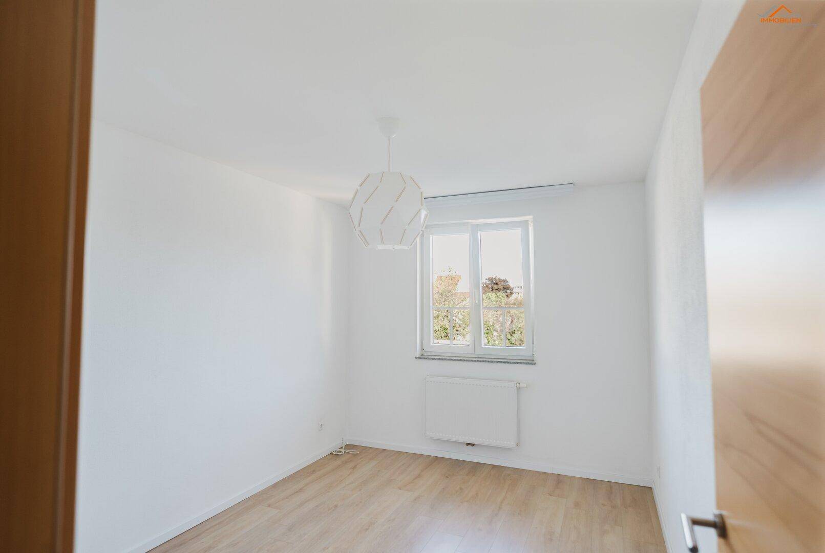Helles Schlafzimmer mit hellem Holzboden und modernem Deckenlicht.