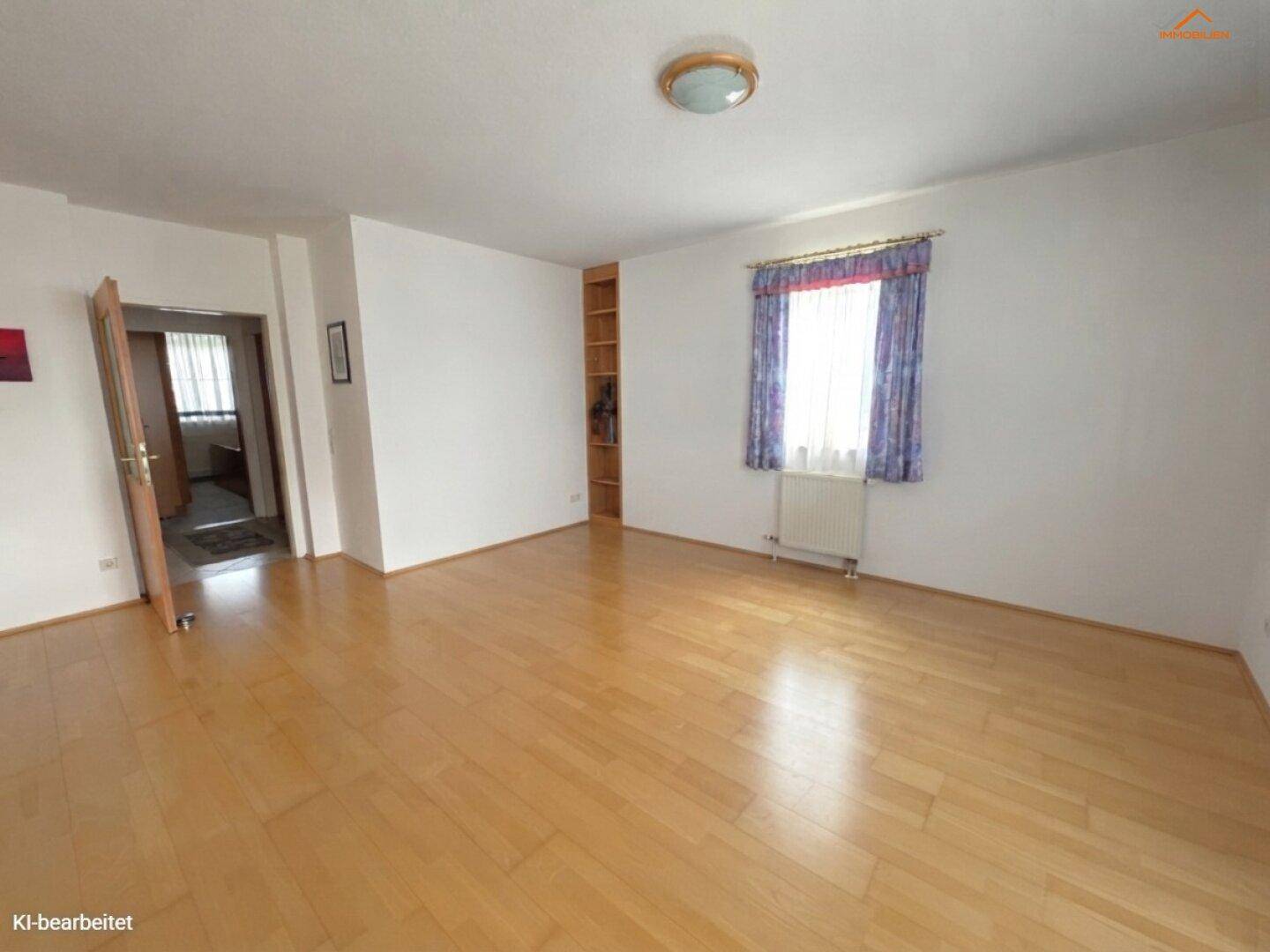 Helles Wohnzimmer mit Parkettboden, einem Fenster und einem Heizkörper.
