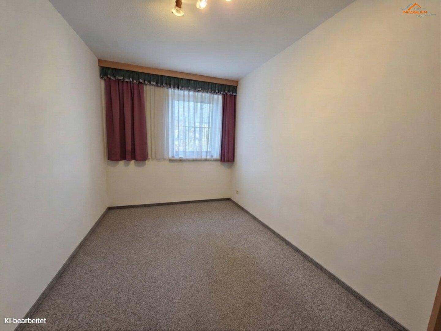 Kleines Zimmer mit Teppichboden, Fenster und Vorhängen in warmen Farbtönen.