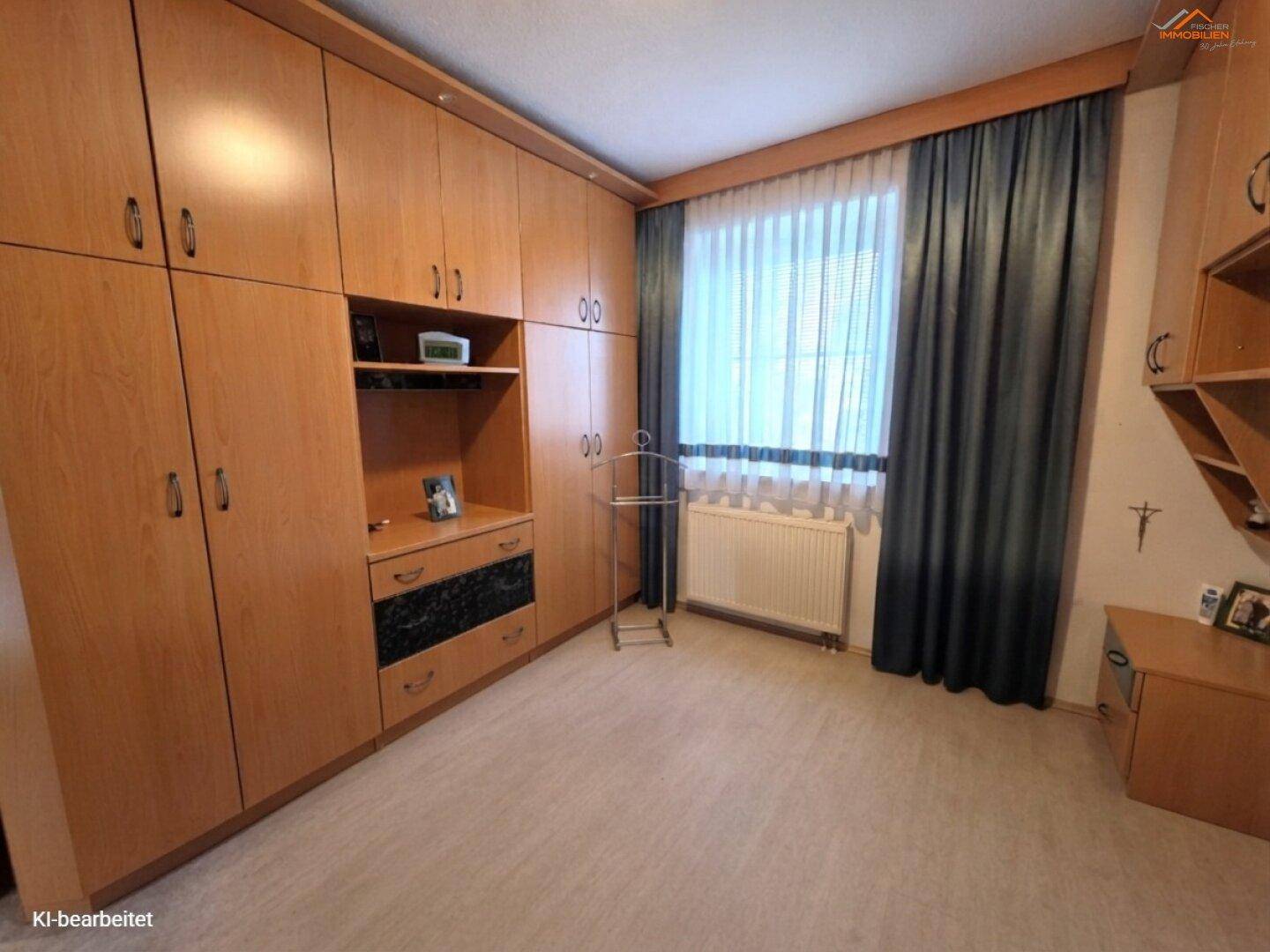 Schlafzimmer mit großen Holz-Einbauschränken und einem Fenster mit Vorhängen.