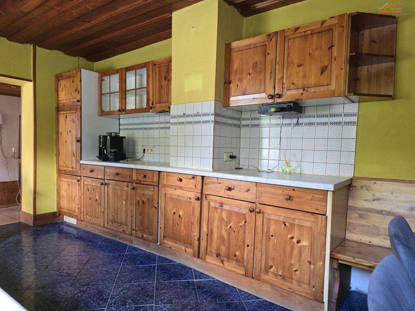 Rustikale Küche mit Holzschränken, blauen Fliesen und Holzbalkendecke.