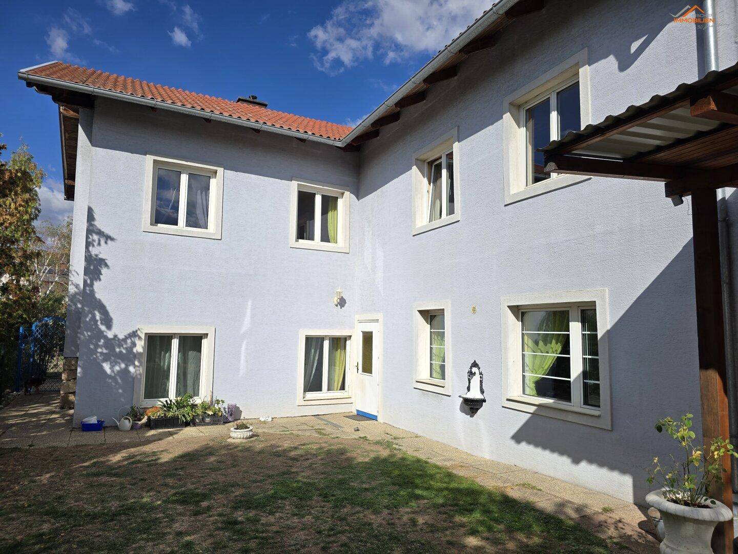 Seitenansicht des Hauses mit mehreren Fenstern und Zugang zum Garten.