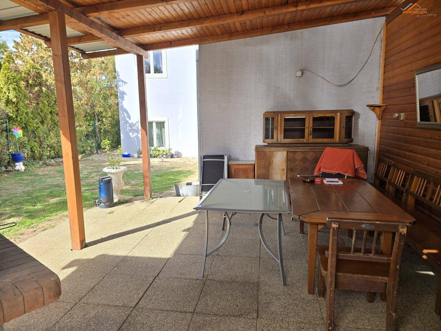 Geräumige überdachte Terrasse mit Sitzgelegenheiten und Zugang zum Garten.