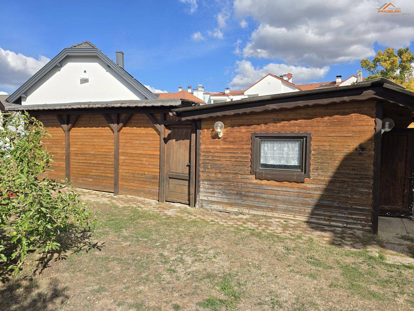 Holzschuppen im Garten mit Fenster und kleiner Tür.