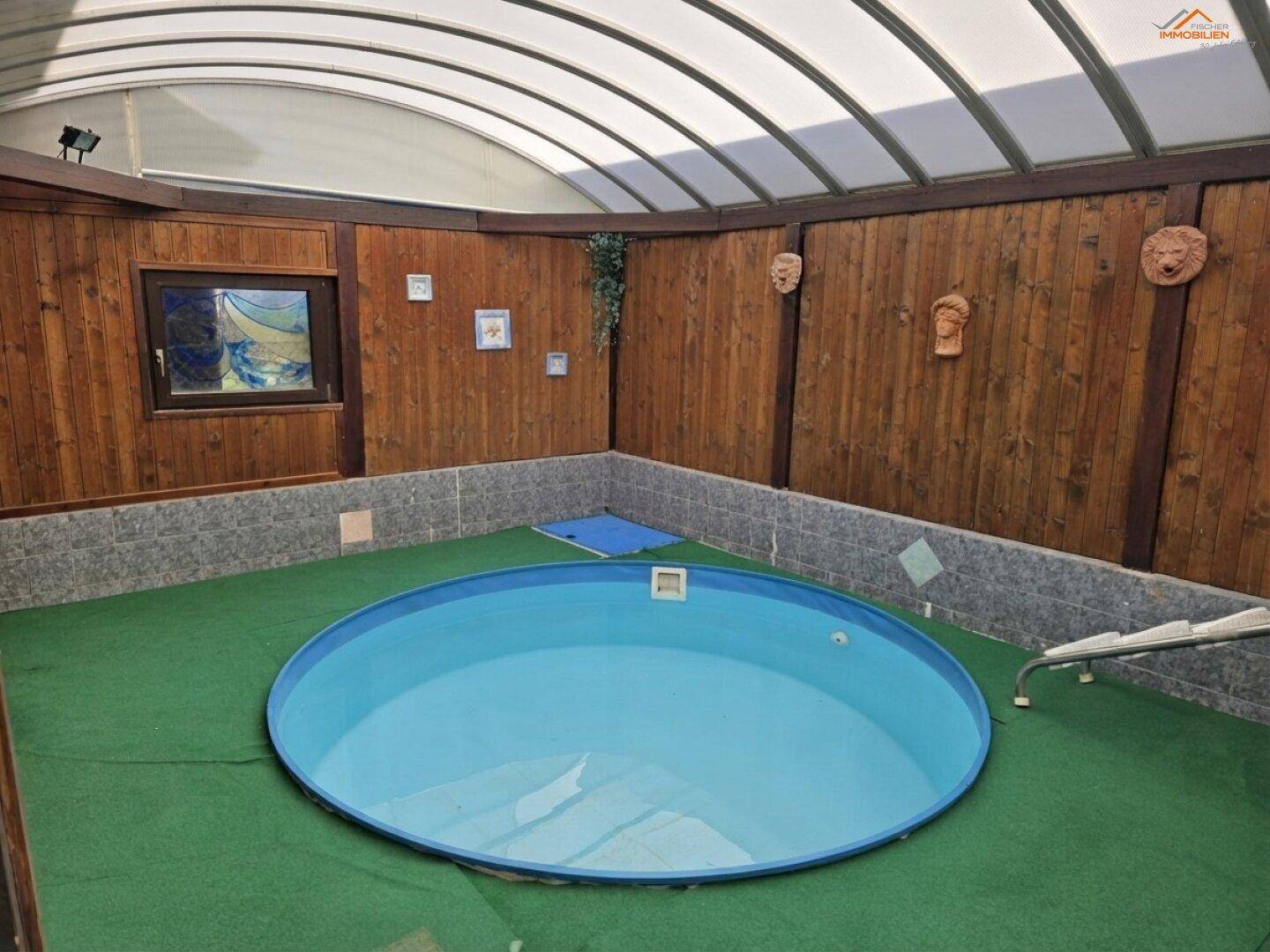 Überdachter Innenpoolbereich mit Holzverkleidung und Kunstrasenboden.