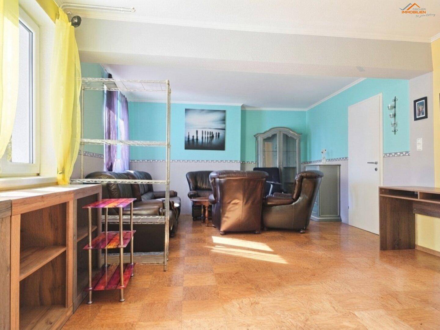 Helles Wohnzimmer mit Ledersofas, farbigen Wänden und Parkettboden.