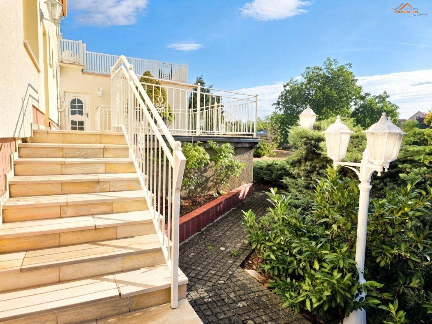 Außentreppe führt zu einer Terrasse mit dekorativen Laternen und gepflegtem Gartenbereich.