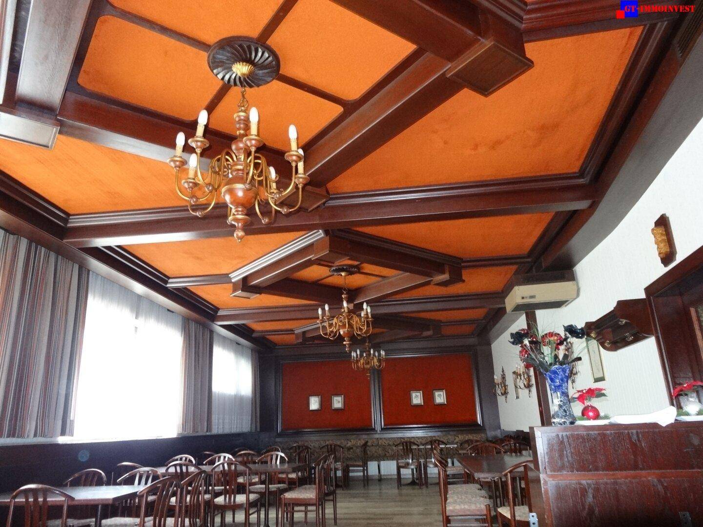 Detailansicht der aufwendigen Holzdecke mit orangefarbenen Paneelen und einem klassischen Kronleuchter.