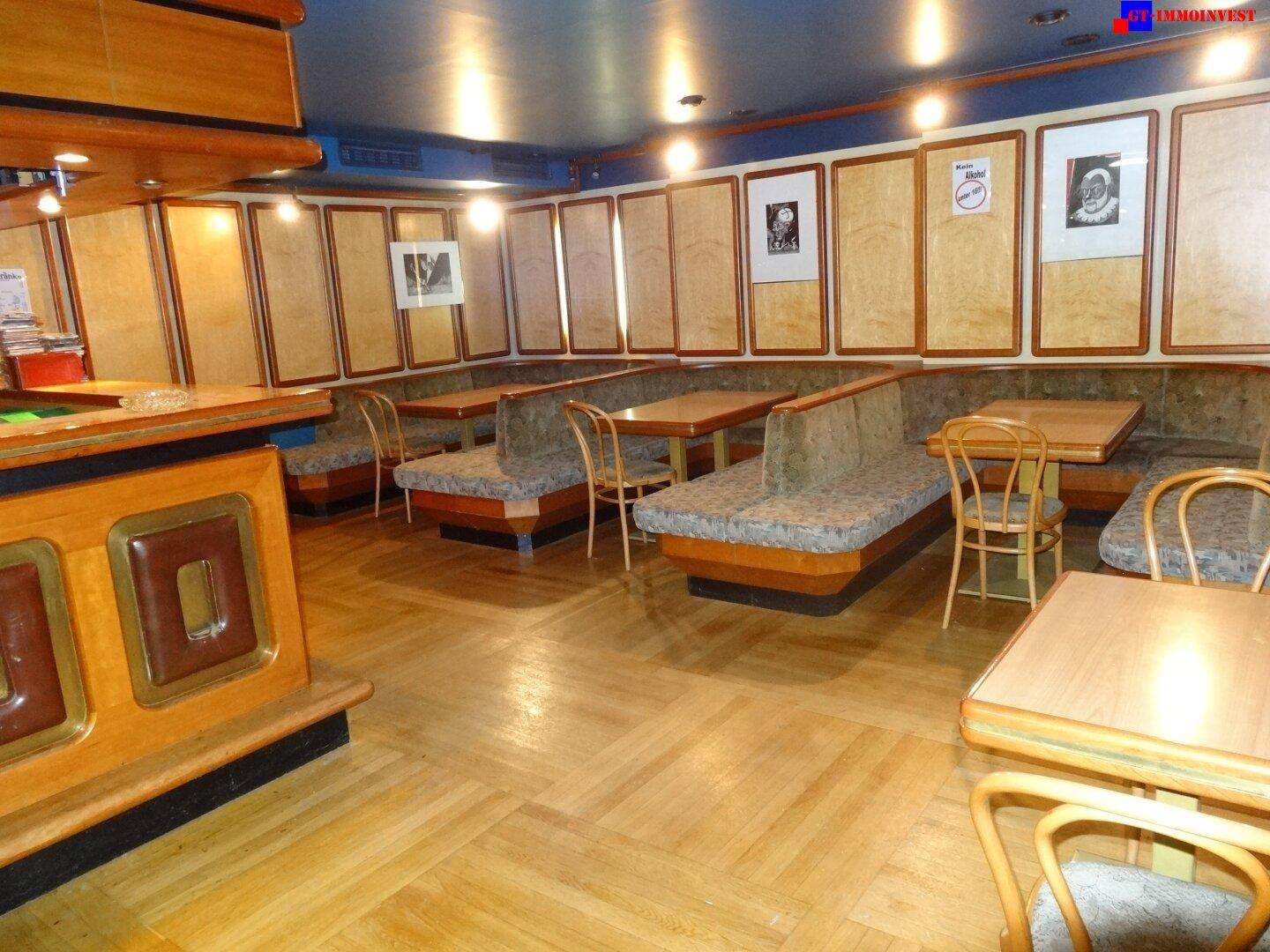 Gemütlicher Sitzbereich neben der Bar mit eingebauten Bänken, kleinen Tischen und Holzvertäfelungen.