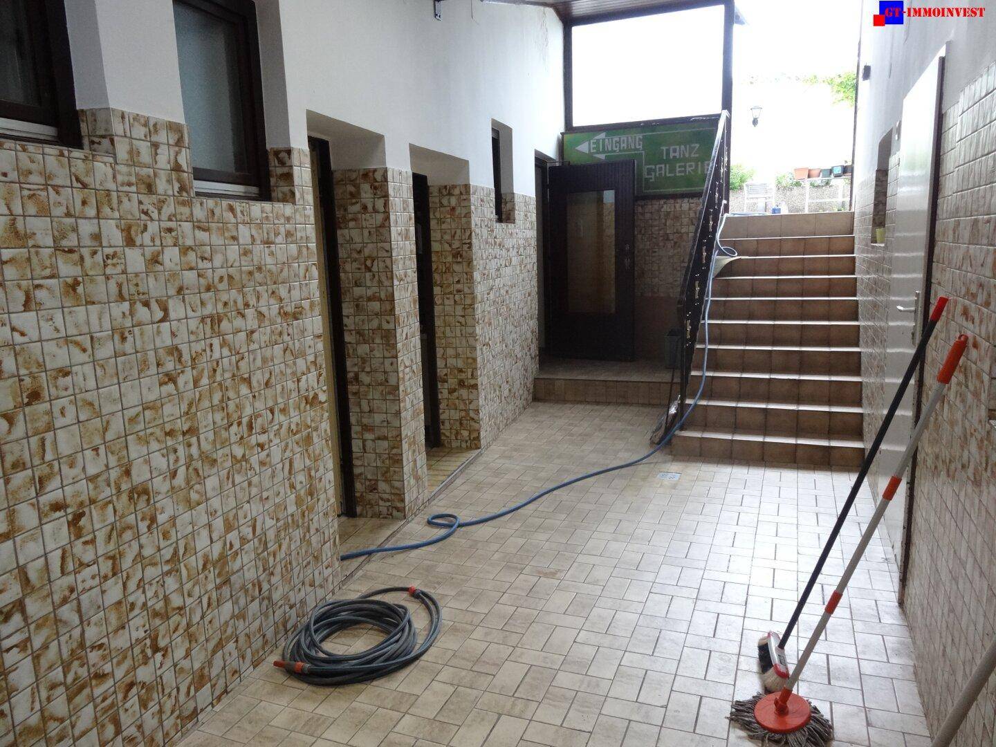 Gefliester Flur oder Eingangsbereich mit Treppe, der zu weiteren Räumen oder einem Tanzsaal führt.