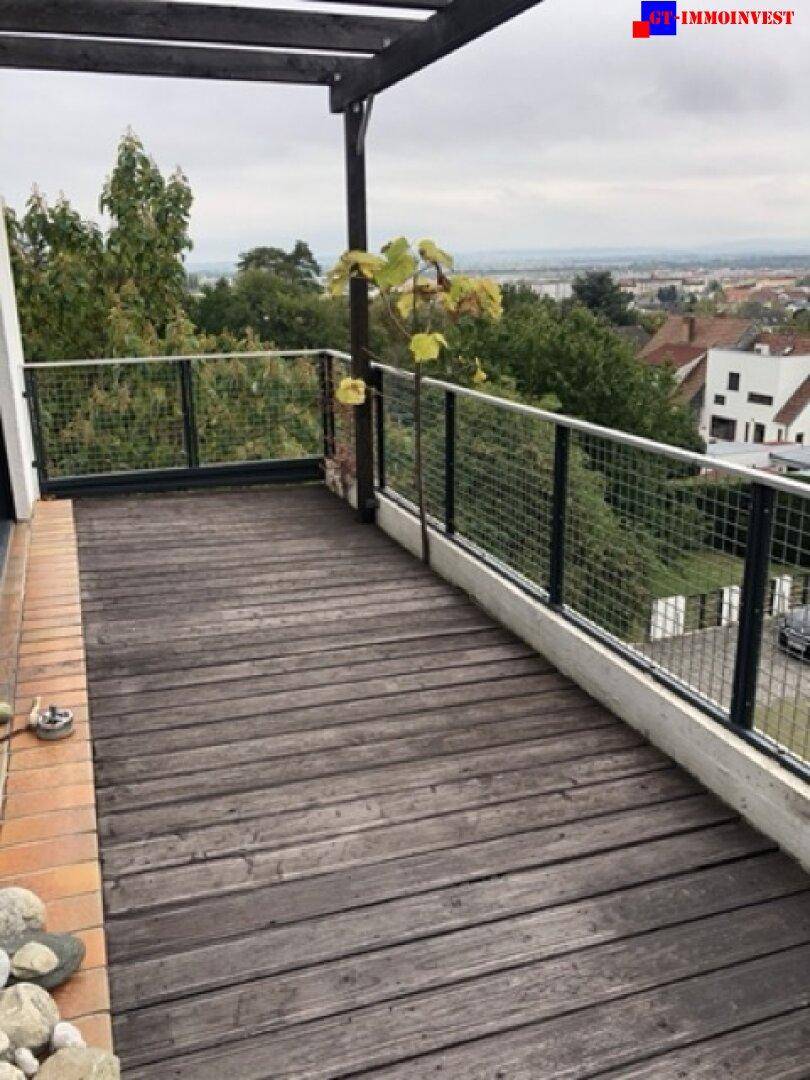Geräumige Holzterrasse mit Metallgeländer und weitem Blick über die Umgebung.