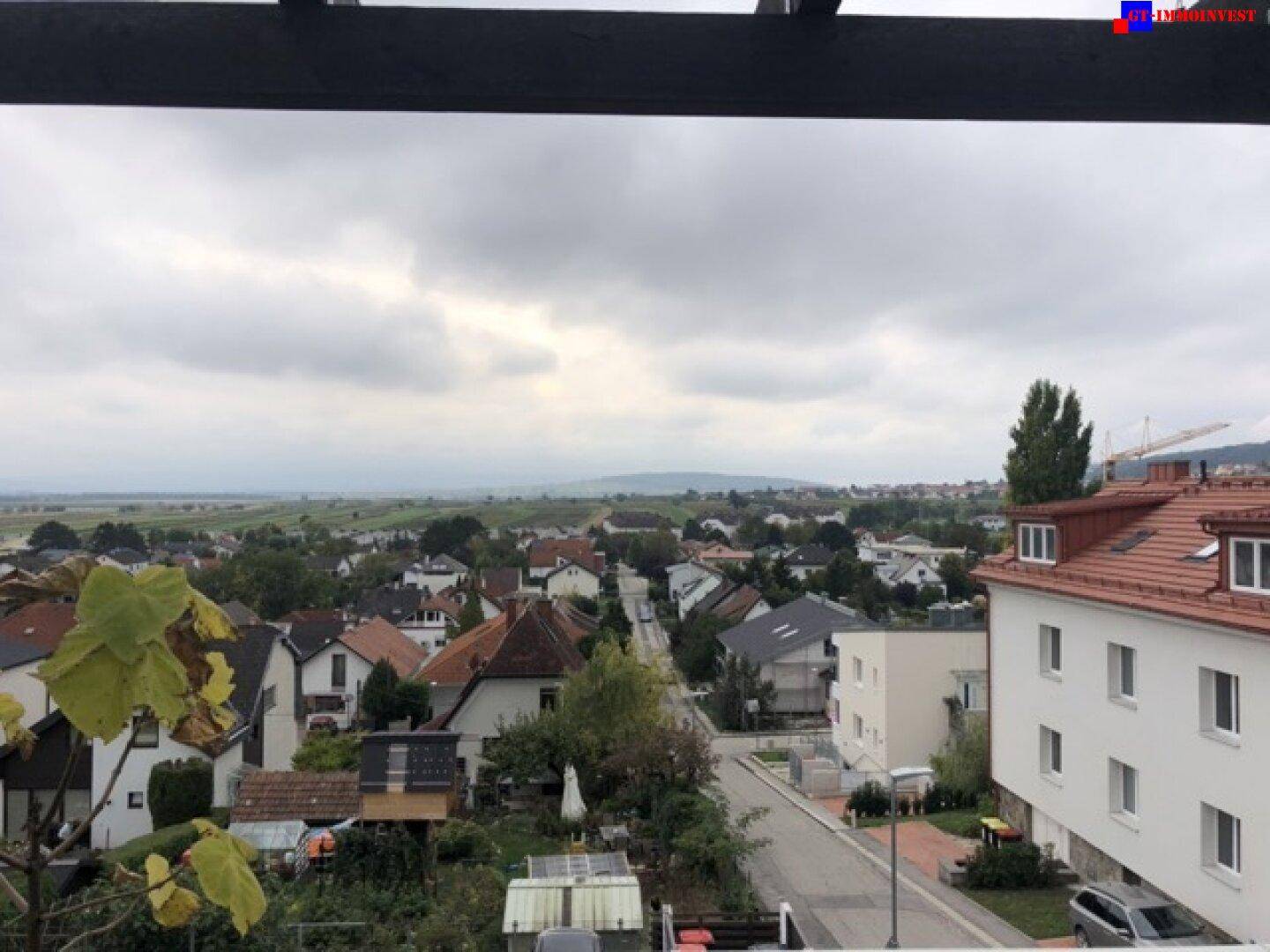 Weitblick über eine Wohnsiedlung und grüne Landschaft unter bewölktem Himmel.