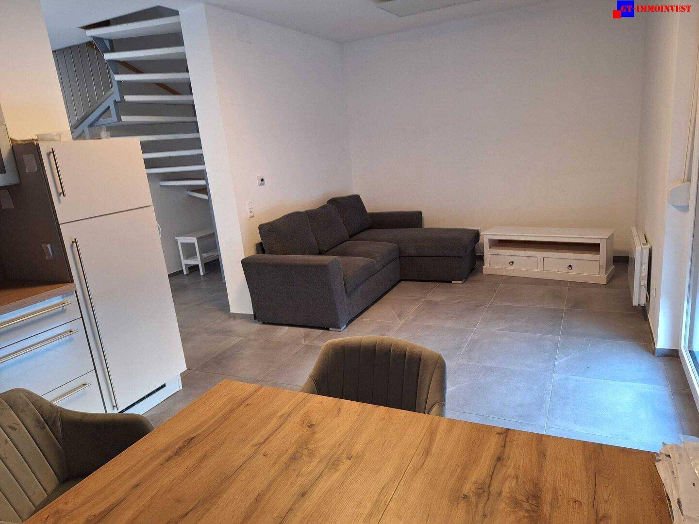 Geräumiger Wohnbereich mit Sofa, TV-Möbel und Treppe zum Obergeschoss.
