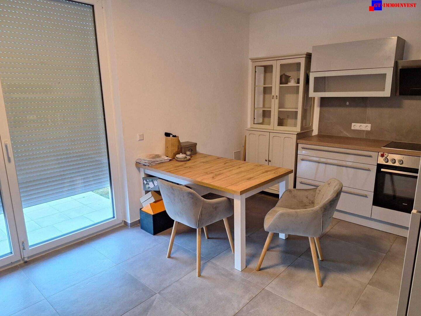 Essbereich in der Küche mit Holztisch, Stühlen und Zugang zur Terrasse durch eine große Fenstertür.