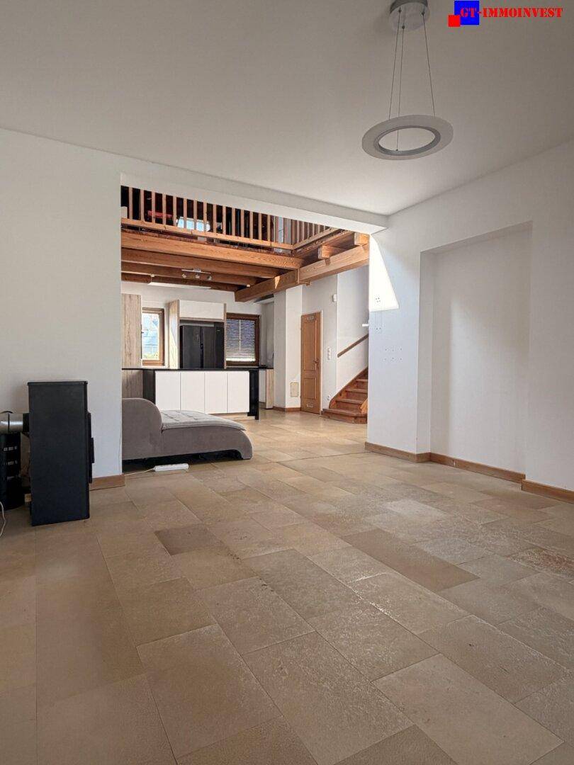 Blick vom Wohnbereich zur modernen Küche und Treppe, mit hellen Fliesenböden und offenem Konzept.