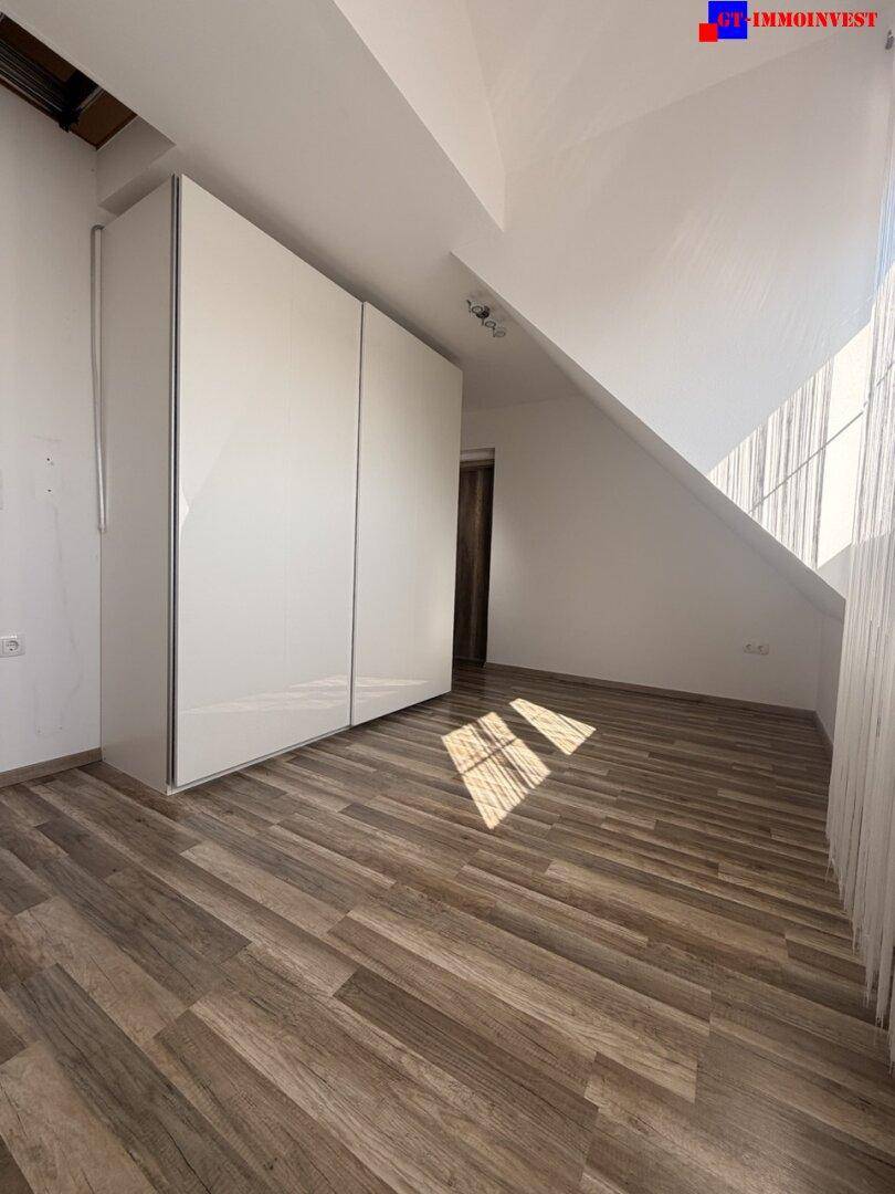 Zimmer mit Laminatboden und großem weißen Kleiderschrank, ideal als Schlaf- oder Ankleidezimmer.