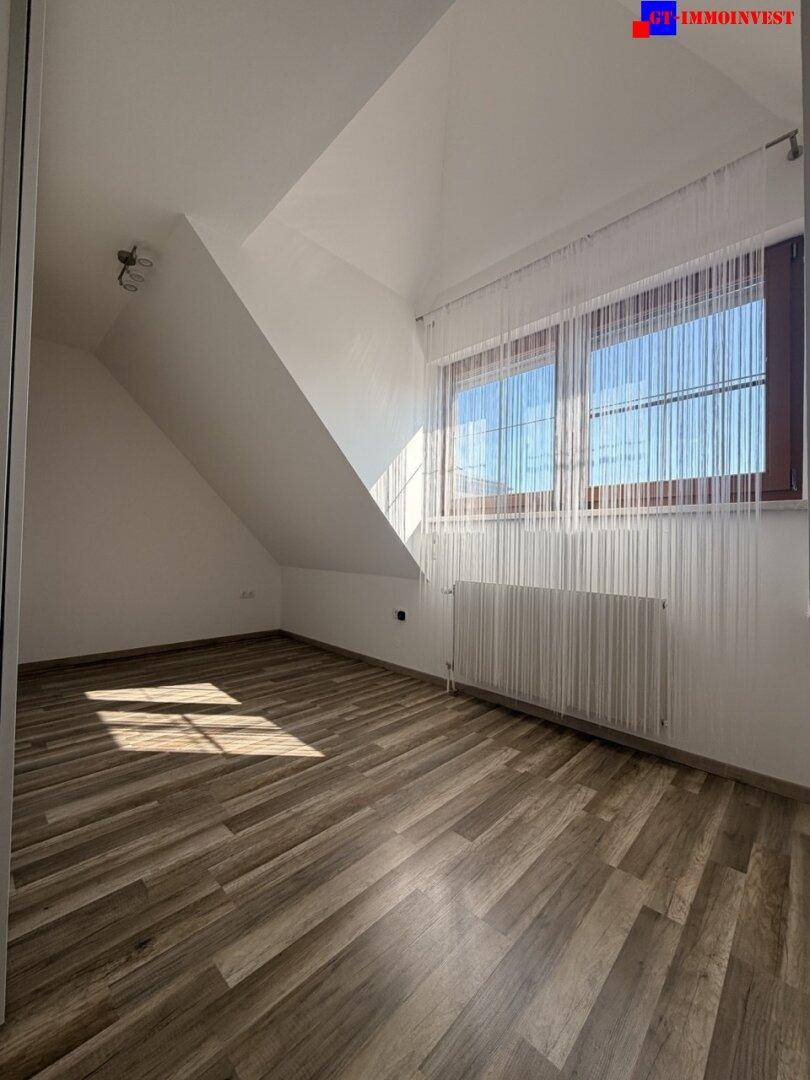 Helles Zimmer mit Laminatboden, Dachschrägen und großem Fenster für viel Tageslicht.