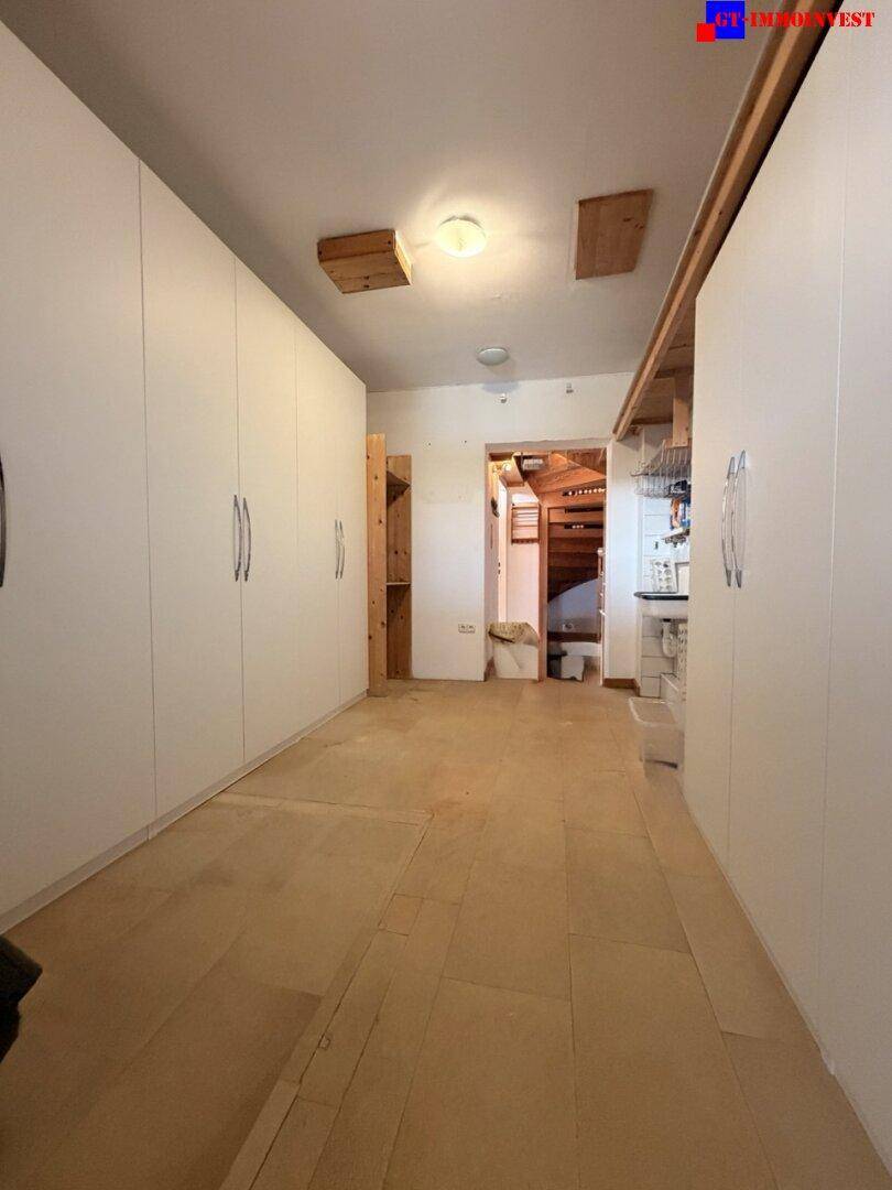 Geräumiger Ankleidebereich mit vielen Einbauschränken und hellem Holzboden.