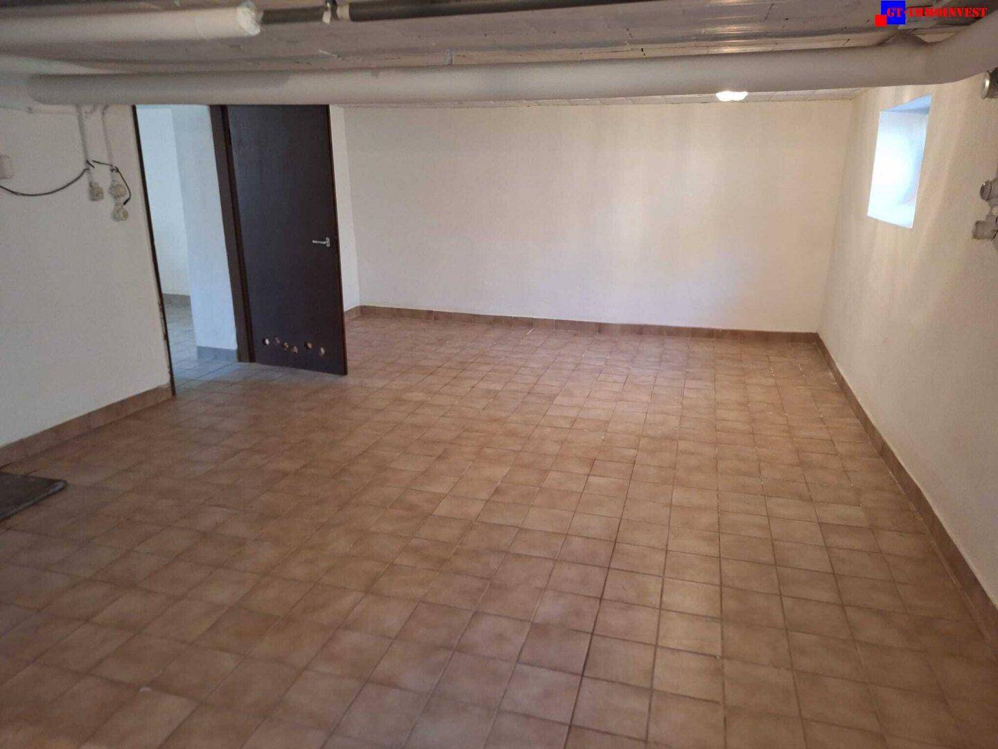 Geräumiger Kellerraum mit Fliesenboden, weiß gestrichenen Wänden und einem kleinen Fenster.