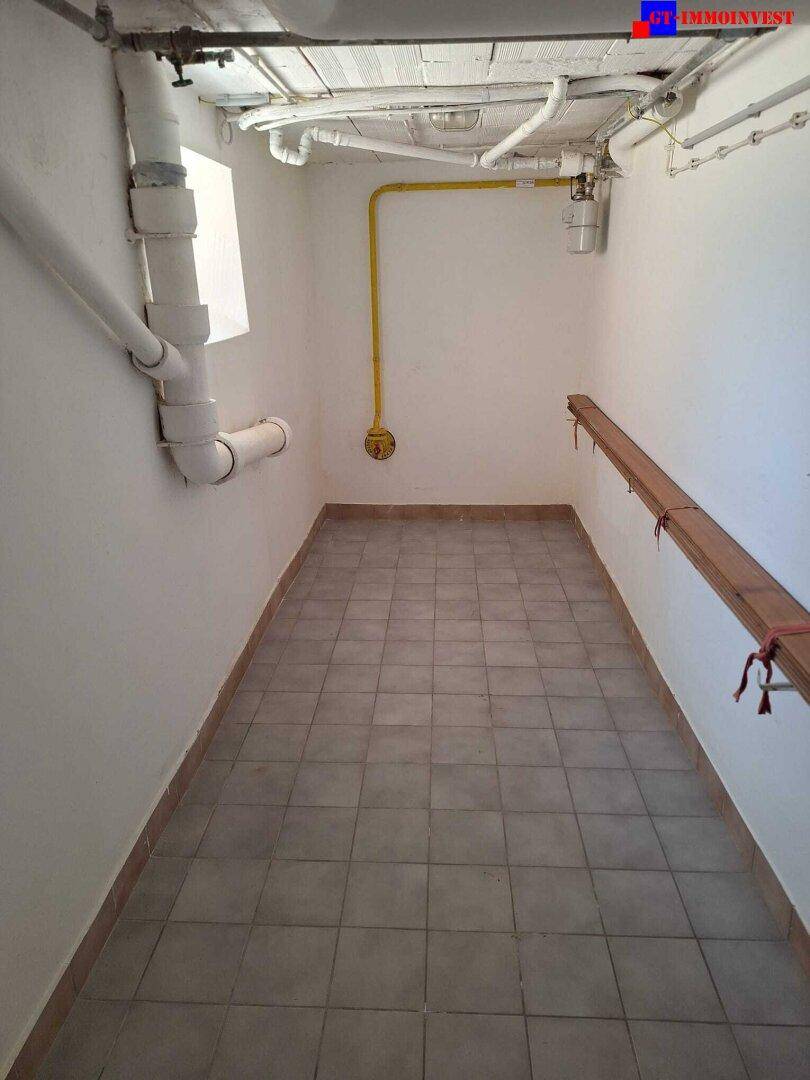 Kleiner Hauswirtschaftsraum im Keller mit Fliesenboden und sichtbaren Rohren an der Decke.
