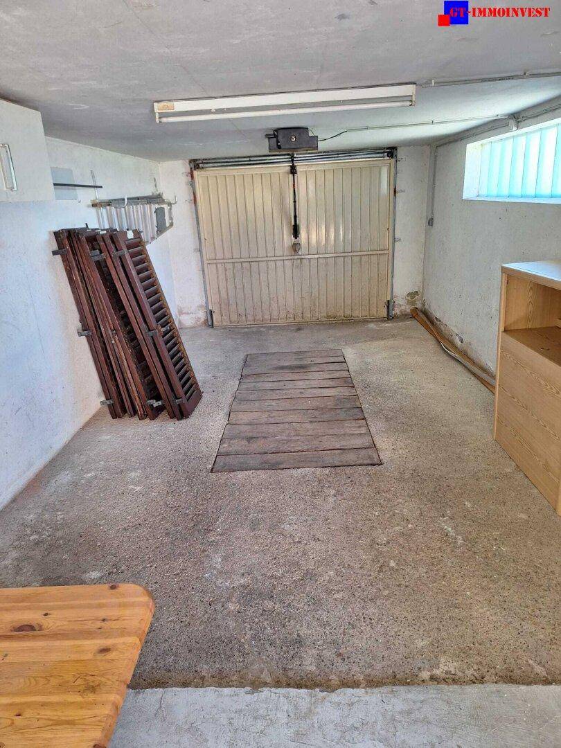 Geräumige Garage mit Betonboden, Garagentor und einem kleinen Fenster.