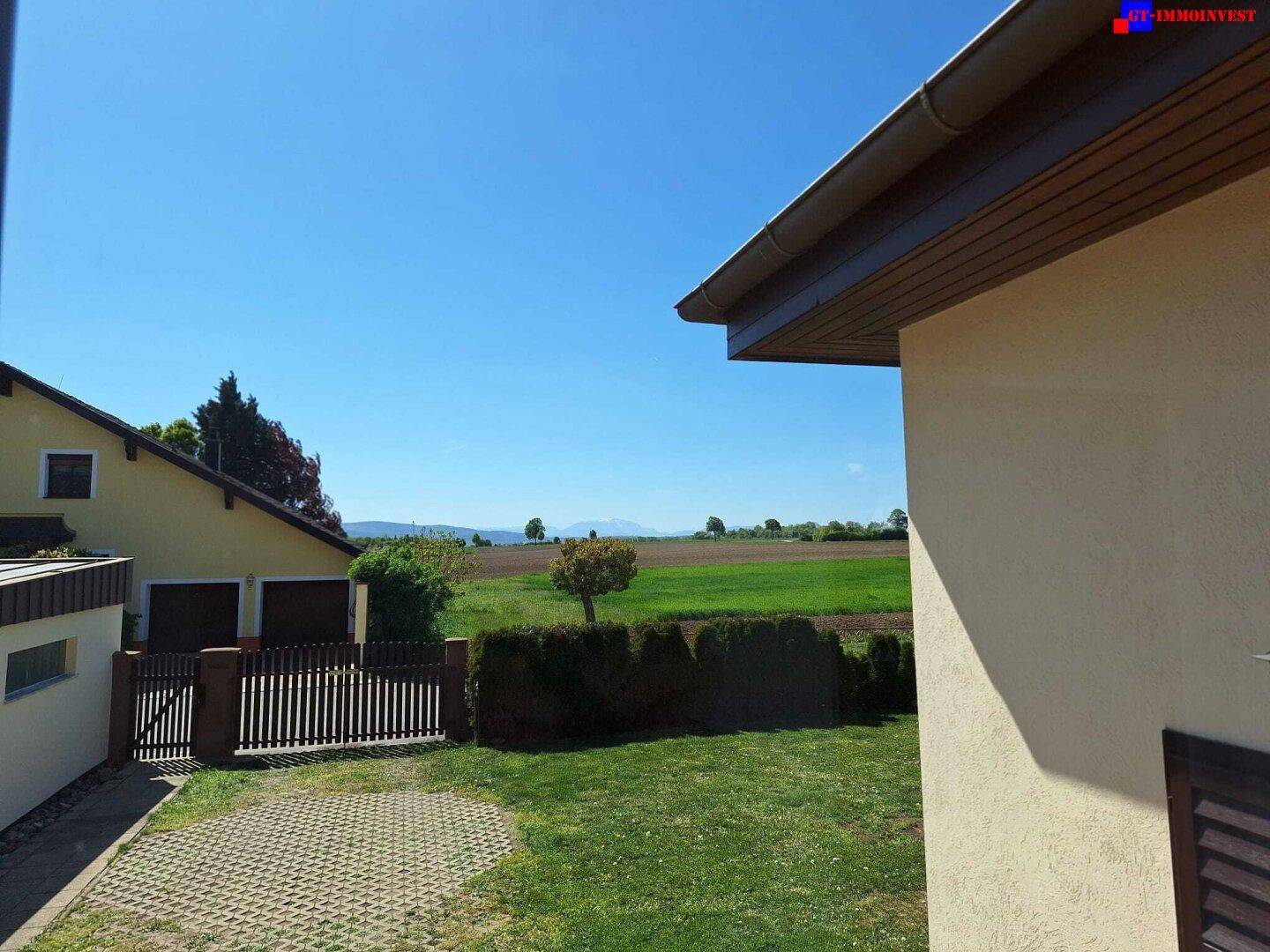 Weitläufiger Blick über grüne Felder und Wiesen bis zu den Bergen am Horizont.
