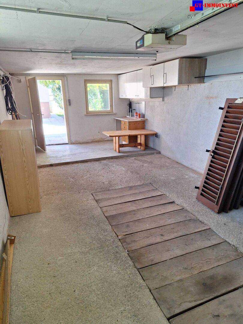Garage mit Betonboden, Zugang zum Außenbereich und einem kleinen Fenster.