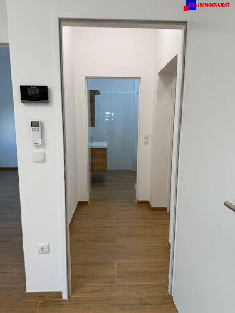 Heller Flur mit Fliesenboden in Holzoptik, der zum Badezimmer führt.
