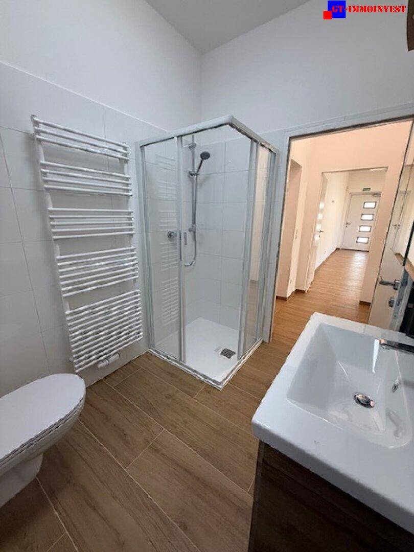 Funktionales Badezimmer mit Duschkabine, WC und beheiztem Handtuchhalter.