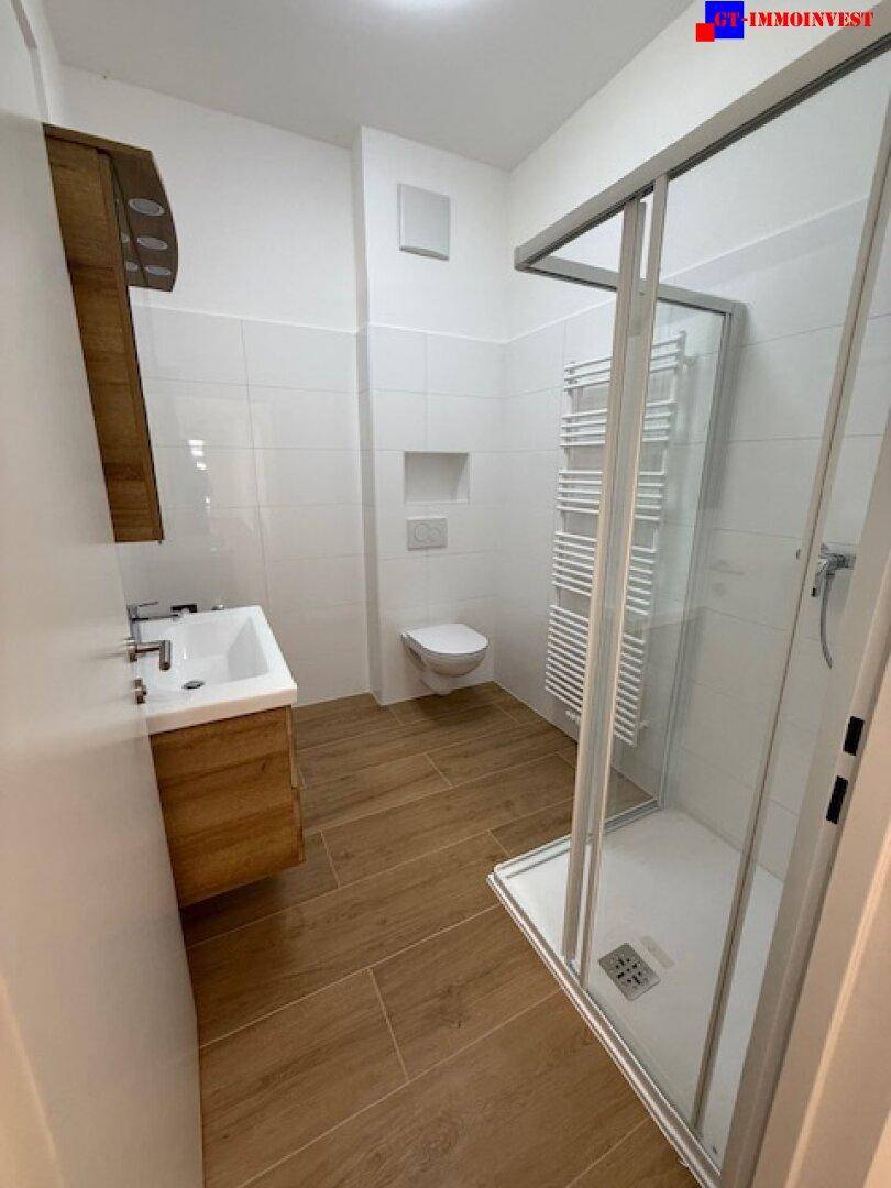 Modernes Badezimmer mit Duschkabine, wandhängendem WC und Holzwaschtischunterschrank.