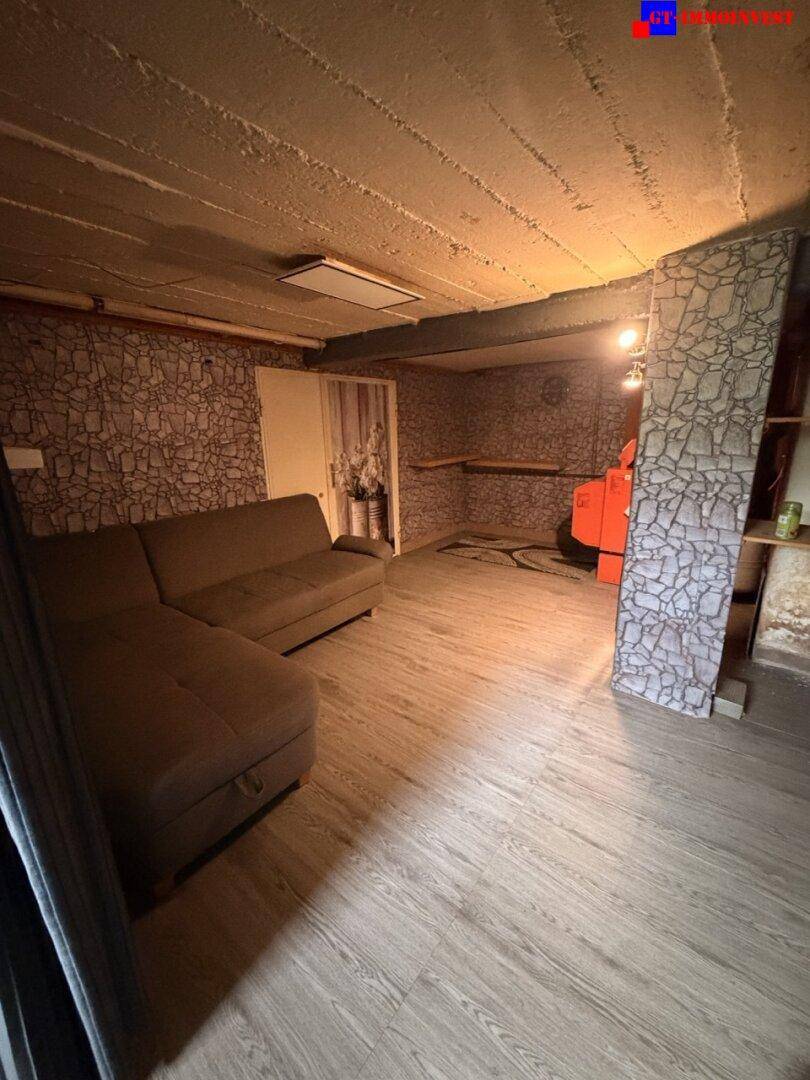 Ausgebauter Kellerraum mit Sofa, strukturierten Wänden und niedriger Decke, als Wohnbereich nutzbar.