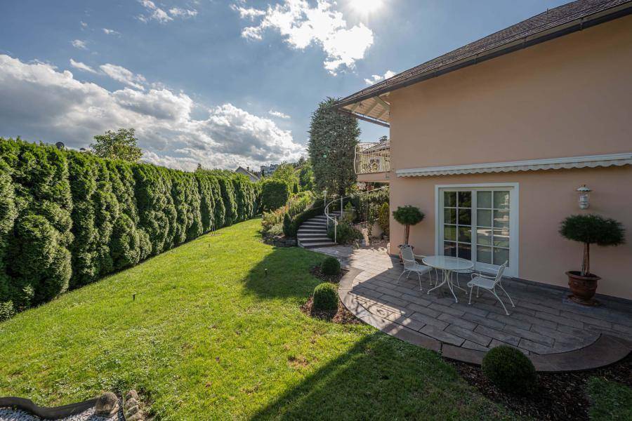 Weitläufiger Garten mit gepflegtem Rasen und hoher Hecke, die Privatsphäre bietet.