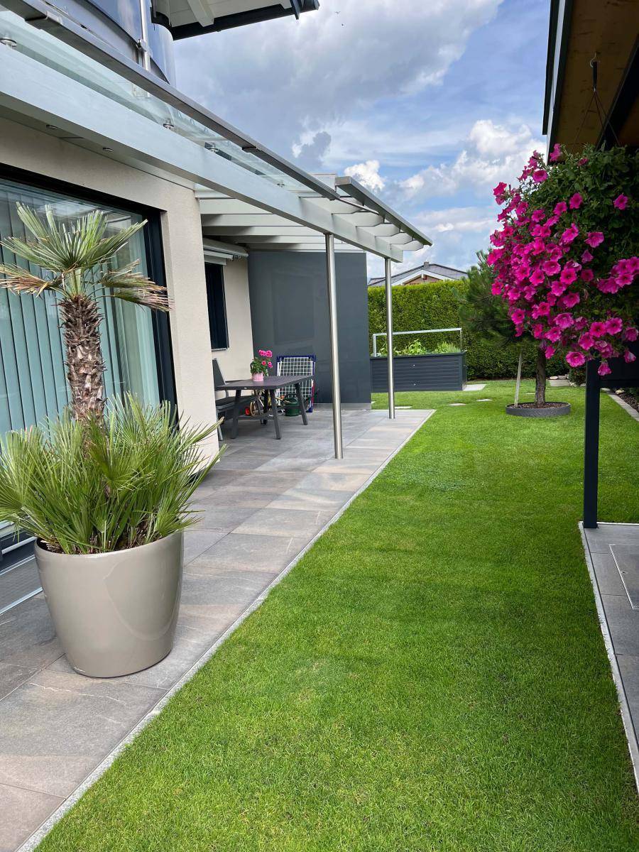 Großzügige Terrasse mit Topfpflanzen und gepflegtem Rasen, ideal für entspannte Stunden im Freien.