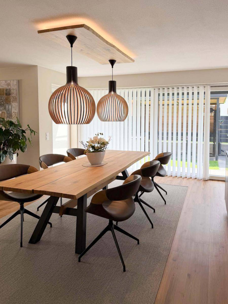 Eleganter Essbereich mit großem Holztisch, modernen Pendelleuchten und Zugang zur Terrasse.