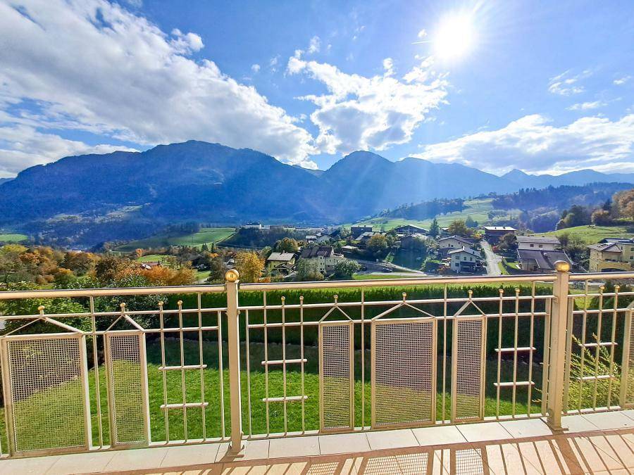 Sonniger Balkon mit Metallgeländer und atemberaubendem Panoramablick auf die Berge und das Tal.