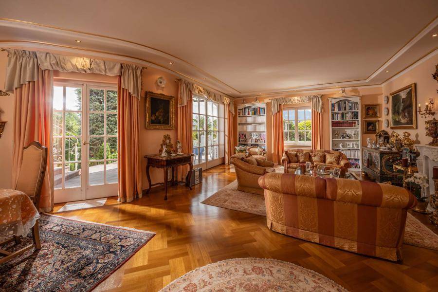 Elegantes Wohnzimmer mit Parkettboden, Stuckdecken und Zugang zu einem Balkon mit Gartenblick.
