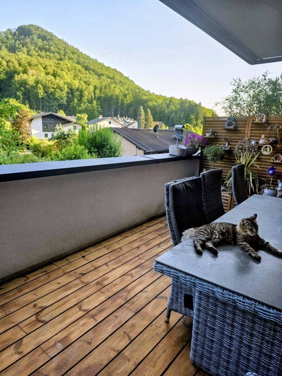 Möblierter Balkon mit Holzboden, Sitzgelegenheiten und Blick auf die grüne Umgebung.