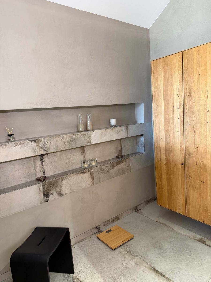Modern gestalteter Raum mit Betonoptikwänden und Holzelementen, möglicherweise Teil eines Badezimmers oder Wellnessbereichs.