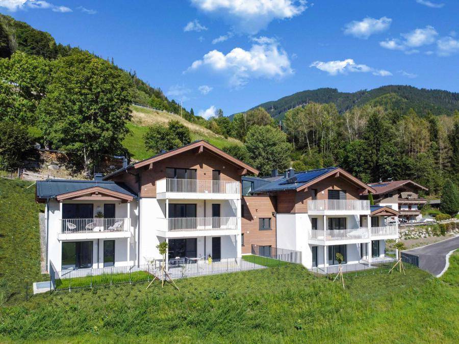 Moderne Wohngebäude in alpiner Landschaft mit Balkonen, großen Fenstern und Bergblick.