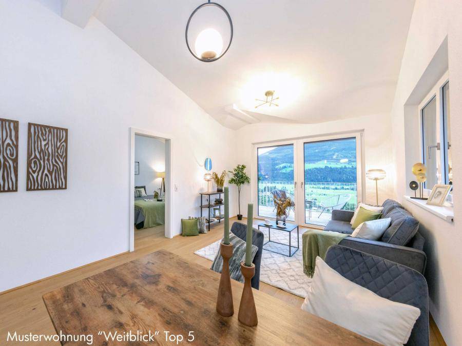 Gemütlicher Wohnbereich mit Holztisch, bequemer Couch und Blick ins Grüne.