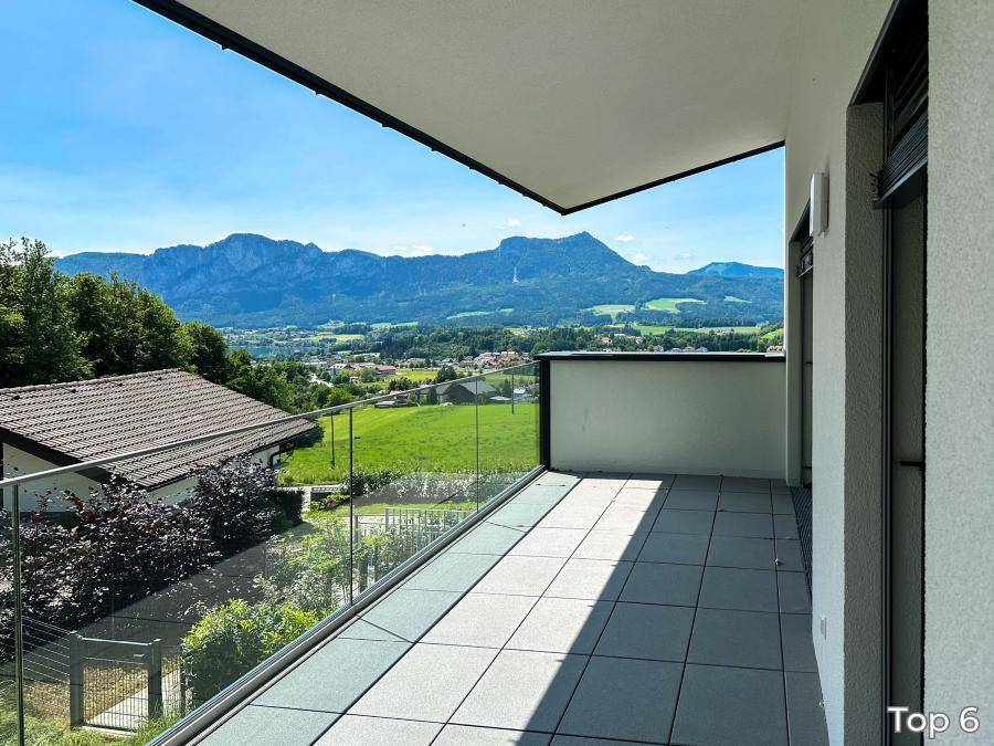 Geräumiger Balkon mit Glasgeländer und atemberaubendem Blick auf die Berge und das Tal.