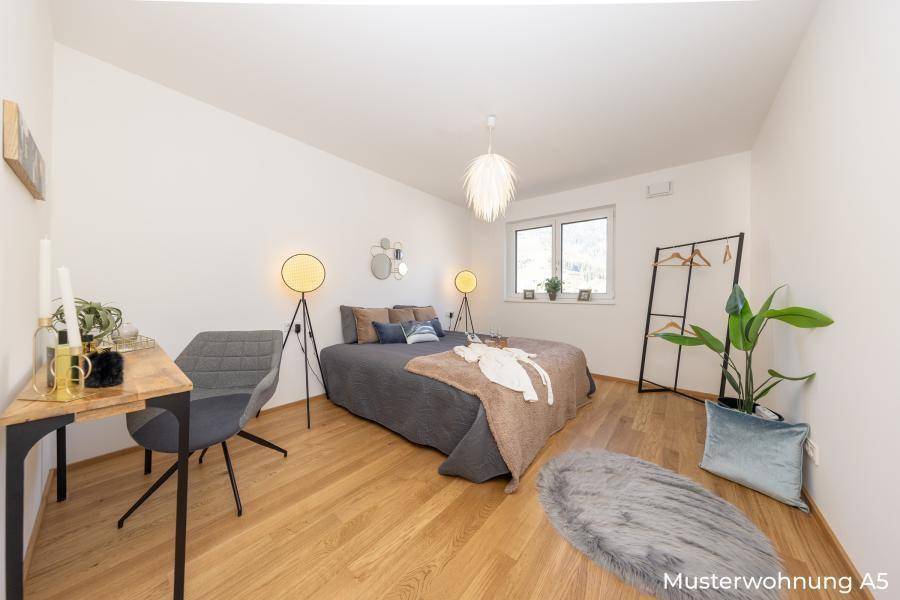 Helles Schlafzimmer mit Holzboden, großem Bett und modernem Schreibtischbereich.
