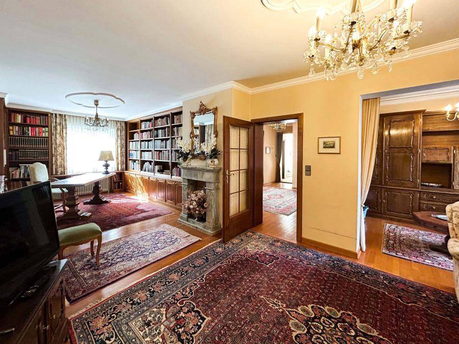 Traditionelles Wohnzimmer mit Kamin, Bücherregalen, Kronleuchter und orientalischen Teppichen.