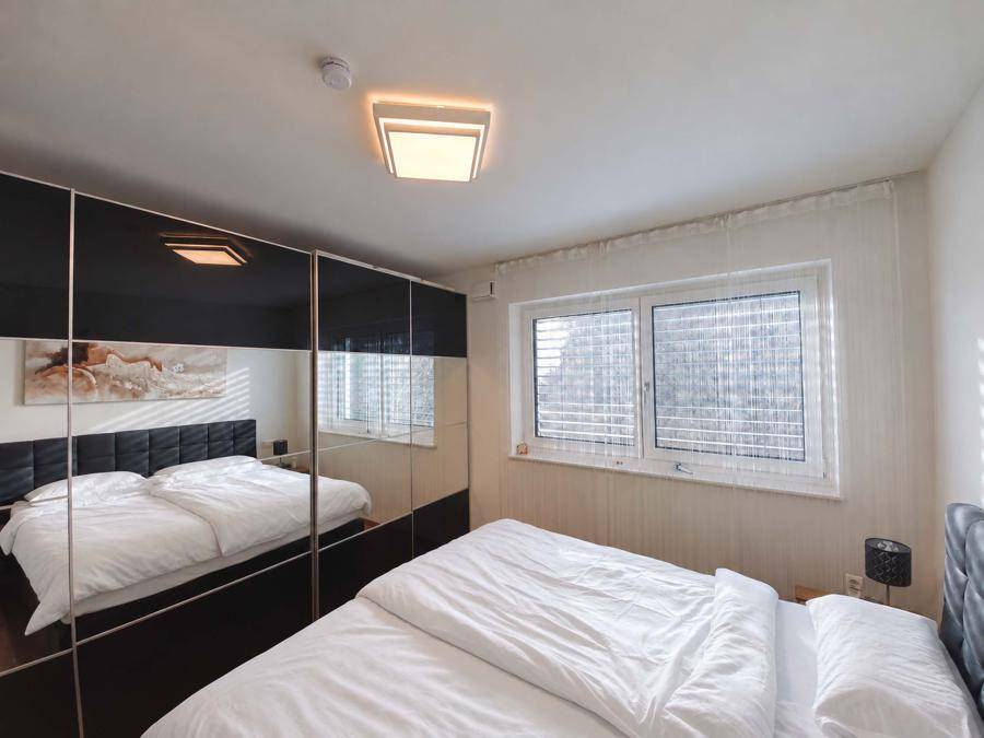 Schlafzimmer mit Doppelbett und eleganten schwarzen Spiegelschränken, die den Raum optisch vergrößern.