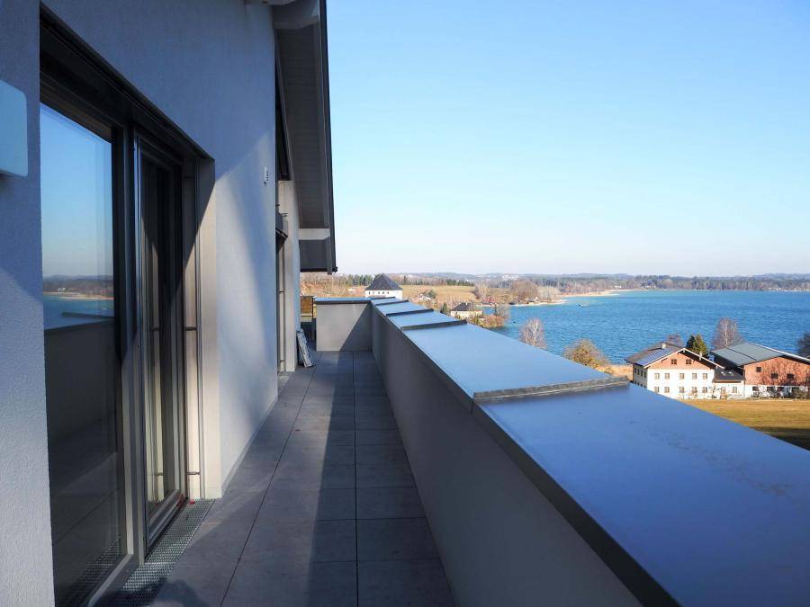 Langer Balkon mit Fliesenboden und Glasgeländer, bietet einen schönen Seeblick.