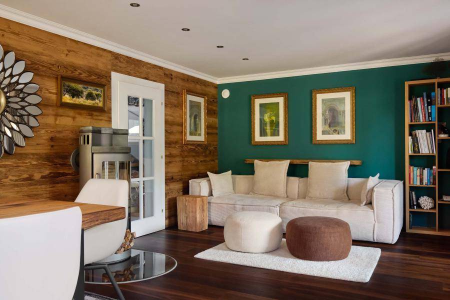 Gemütliches Wohnzimmer mit Holzwänden, Kaminofen und moderner, heller Einrichtung.