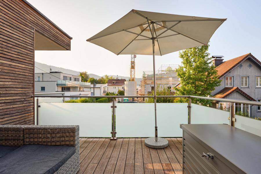 Geräumiger Balkon mit Holzboden, Sonnenschirm und weitem Blick über die Umgebung.