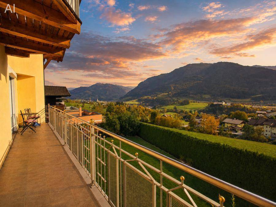 Balkon mit atemberaubendem Sonnenuntergang über den Bergen und dem grünen Tal.